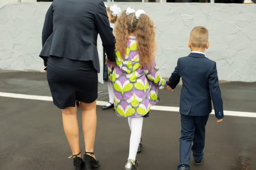 Parent takes children to school. Mother in skirt.