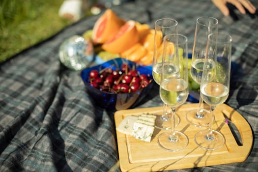 Picnic details. Champagne glasses and cheese. Food on street. Drinks and fruits. Breakfast in nature.