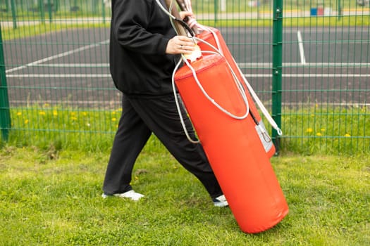 Man carries sports equipment. Preparation of training on street. Equipment for practicing blows. Sports details.