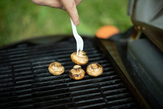 Mushrooms are grilled. Picnic details. Food on steel grate. Cooking in summer.