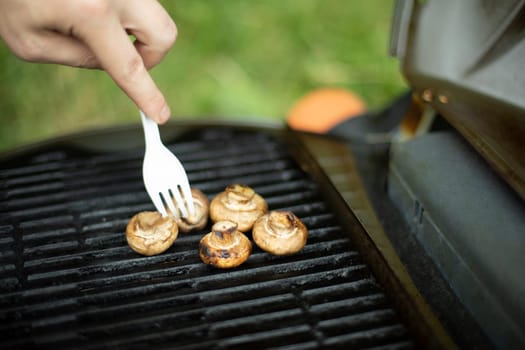 Mushrooms are grilled. Picnic details. Food on steel grate. Cooking in summer.