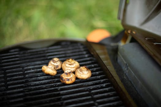 Mushrooms are grilled. Picnic details. Food on steel grate. Cooking in summer.