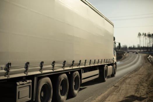 Truck is driving down highway. Transparation of goods on road. Heavy truck carries goods.