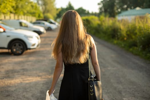 Girl in parking lot. Girl with long hair and black dress. Woman on street in summer. Man is walking from party.