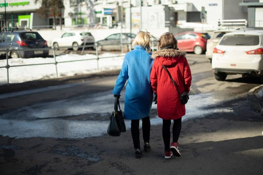 Women walk through city. Girls in parking lot. Citizens on street. Walk in spring.