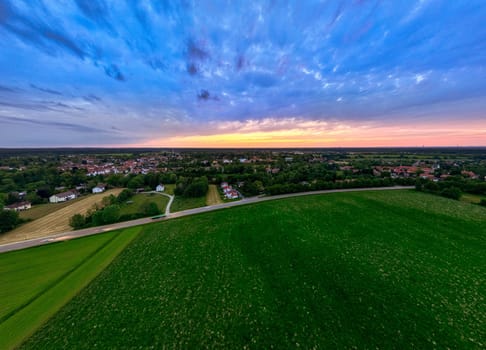 Sunset Glow Over Green Fields and Distant Town.