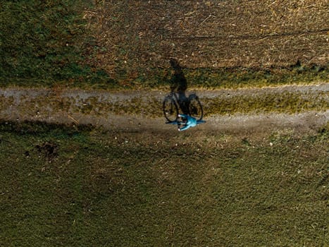 A man is riding his bike over a rural path, top down aerial view