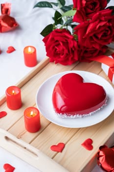 Valentines day. heart shaped glazed valentine cake and candles in wooden tray