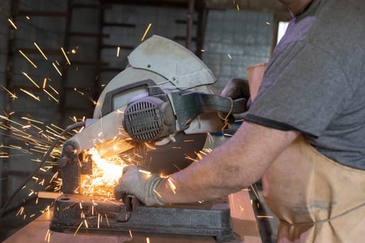 Circular saw in garage. Sparks from metal. Production of construction.