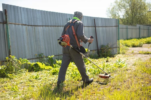 Mowing grass. Worker mows lawn. Gardener with gasoline-powered lawn mower.