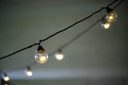 Light bulbs on wires. Garlands in interior. Incandescent lamp. Warm light.