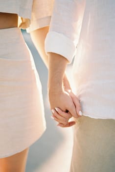 Man and woman are standing holding hands. Cropped. Faceless. High quality photo