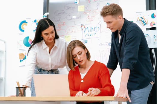 Professional business team working together by using laptop in start up project at meeting in front of glass board with mind map while colleague brainstorm and discuss about strategy. Immaculate.