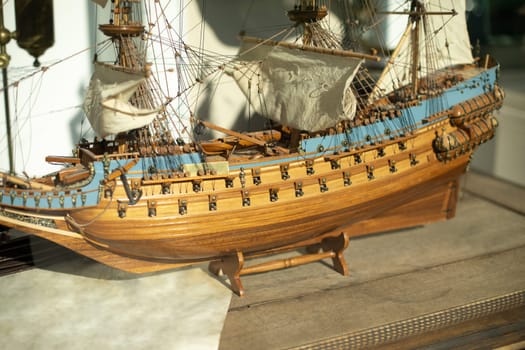 Small ship. Model of frigate. Sails on wooden ship. Masts on deck.