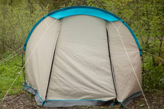 Tourist tent in forest. Tent for sleeping in nature. Equipment for going to park. Awning protects against rain.