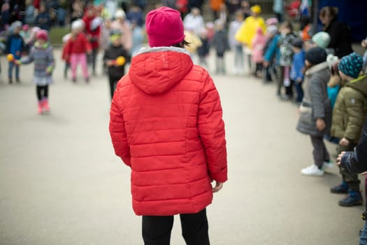 Child in red jacket. Child at children's festival. Children's play on street.