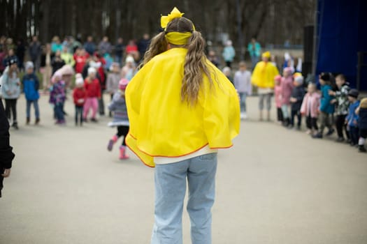 Girl entertains children in square. City holiday in park. Animator entertains children on street.