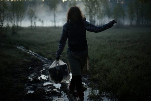 Girl walks in fog in morning. Rest in wild. Fog in swamp. Man carries things to water.