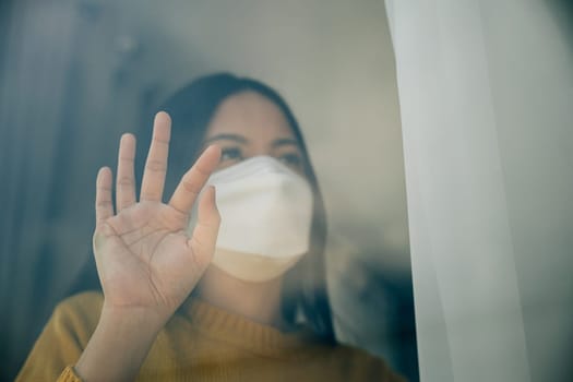 A woman wearing a medical mask practices self-isolation at home emphasizing COVID-19 prevention during the outbreak and the concept of home quarantine.