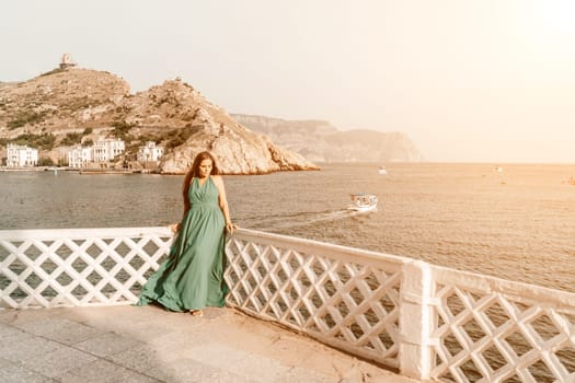 Woman sea trevel green dress. Side view a happy woman with long hair in a long mint dress posing on a beach with calm sea bokeh lights on sunny day. Girl on the nature on blue sky background