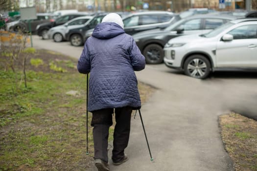 Woman with walking poles. Pensioner is engaged in race walking. Walk for health. Old woman does physical exercise.