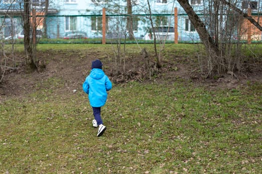 Child runs to fence. Kids got lost in street. Boy hurries home. Blue jacket.