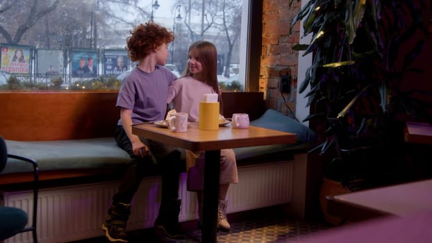 A children's date in a cafe. Stock footage. A children's holiday where a boy gives a girl a soft toy and they drink hot cocoa. High quality 4k footage