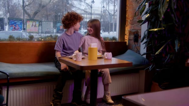 A children's date in a cafe. Stock footage. A children's holiday where a boy gives a girl a soft toy and they drink hot cocoa. High quality 4k footage
