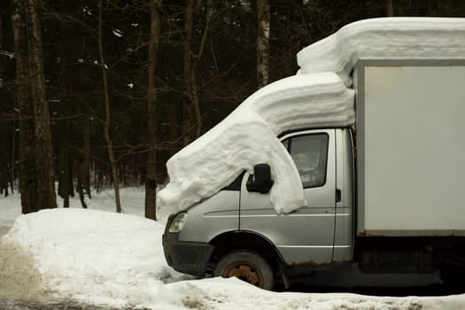 Snow by car. Trucks in parking lot. Car is parked in snow.