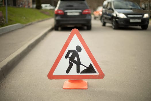 Road sign of road repair. Careful repair. Driver warning. Triangular sign on road.
