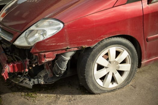 Wrecked car. Damaged transport. Crumpled metal. Wheel and headlight.