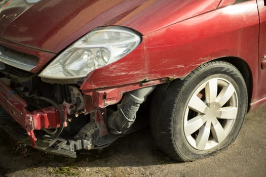 Wrecked car. Damaged transport. Crumpled metal. Wheel and headlight.