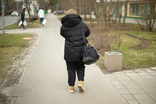 Woman in black clothes walks down street. Woman in town. Walk through city area.