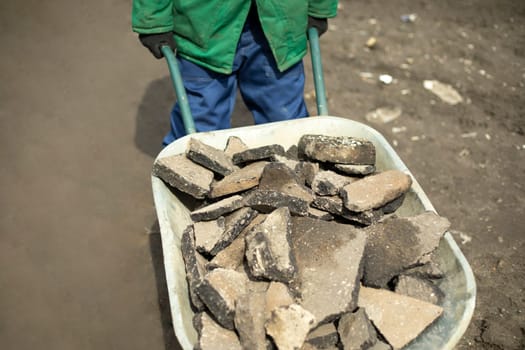 Transportation of broken stone. Worker dismantles block of stones. Construction debris on street. Stone removal.