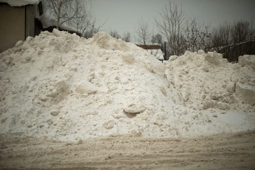 Snow on road. Big mountain of snow on highway. Result of cleaning road. After snowstorm outside.