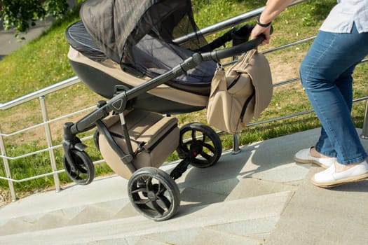 Descent of baby stroller on stairs. Woman lowers stroller with child. Stairs in park. Ramp for lifting vehicles.