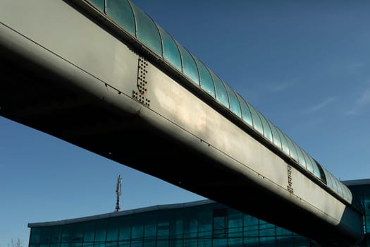 Tunnel over road outside. Pipe for pedestrians. Infrastructure at transport hub. Details of way around city. Transport architecture.