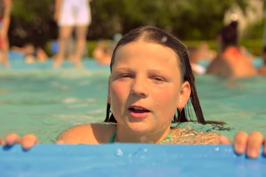 A little girl at the edge of the pool. Small child on the edge of the pool. Vibes of the 80s. Small girl in the pool. The concept of summer, water fun and summer fun.