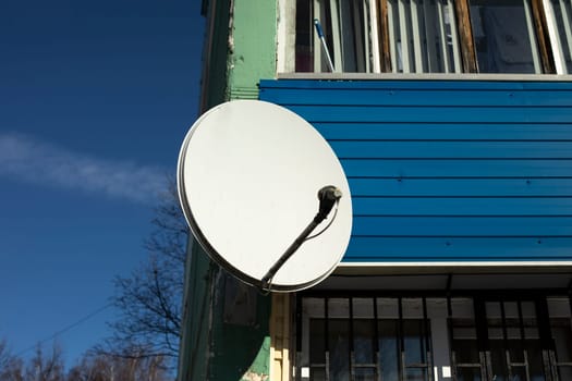 Satellite antenna on house. Radio signal reception. White plate. Radio receiver on street.