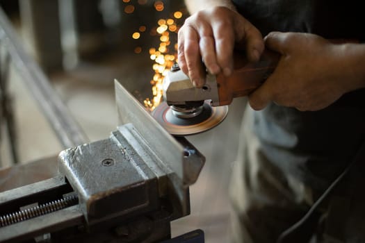 Grinding steel. Worker grinds metal. Work in garage. Electric tool in hand. Create flat surface.
