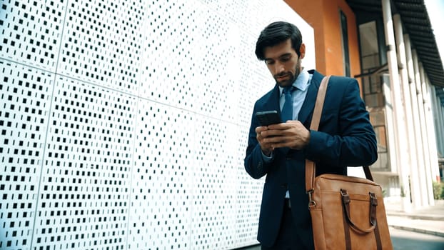 Smart manager looking at mobile phone and walking at street while wearing suit. Skilled investor looking mobile phone to checking sales or working while holding coffee cup. White background. Exultant.