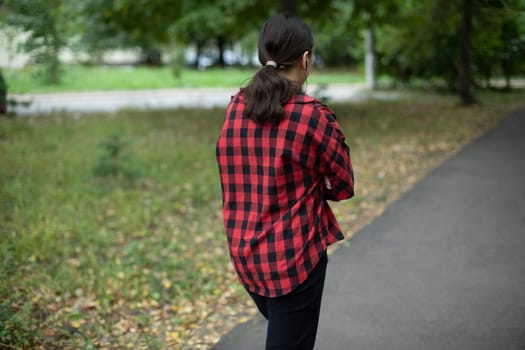 Red shirt. Man from behind in park. Long black hair. Walk through park in autumn.