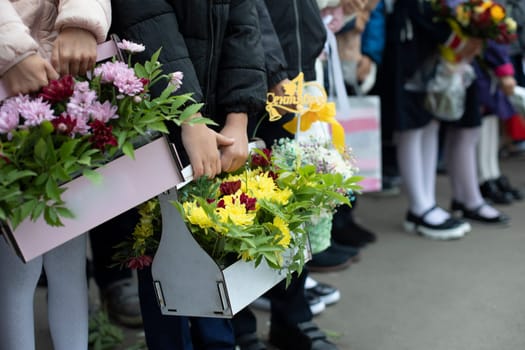 Children hold flowers. Kids are on holiday. First day of school. Flowers for trailer.