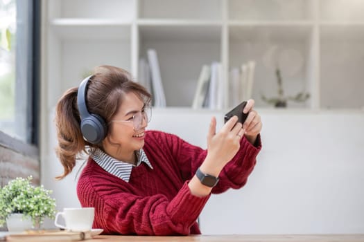 Excited Asian woman playing online game on her smartphone with live broadcasting on internet. cell telephone technology e-commerce concept.