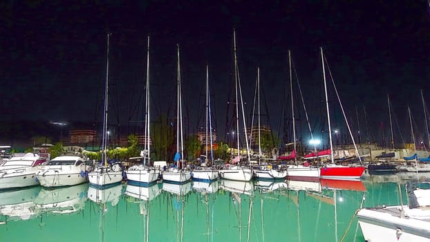 Sailboats docked in a marina on a calm summer night.