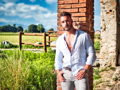 A man leaning against a brick wall in front of a corn field