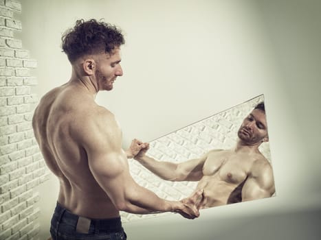 A man holding a mirror with his shirt off