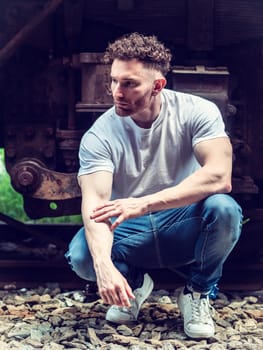 A man sitting on a train track next to a train. Photo of a man sitting on a train track next to a train