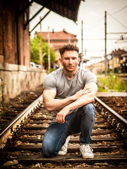 A man sitting on a train track with his arms crossed