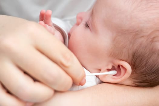 Attentive mother adopts traditional methods, cleaning her baby's ear with utmost precision and care